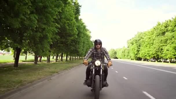 Велосипедист їде на мотоциклі на дорозі, оточеній деревами — стокове відео
