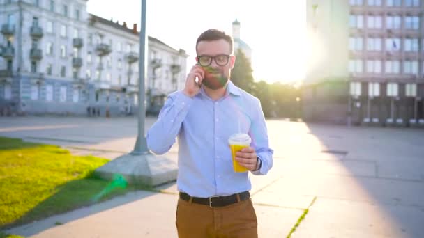 Mann spricht mit Smartphone und trinkt Saft auf der Straße — Stockvideo