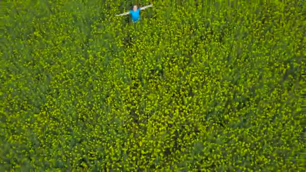 Jeune femme avec les bras tendus dans un champ de canola jaune 