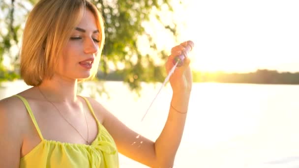 Jeune belle blonde soufflant des bulles de savon à l'extérieur au ralenti — Video