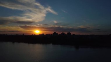 Ağaçlar ve şehrin şafak - hava göl üzerinde uçan videoya