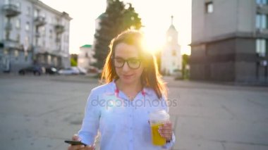 Smartphone üzerinde konuşmak ve sokakta yürürken suyu içme kadın