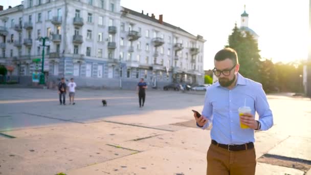 Man talar på smartphone och dricka saft som gick på gatan — Stockvideo