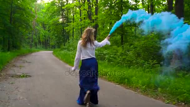 Mulher em roupas bonitas corre pela floresta acenando fumaça colorida — Vídeo de Stock
