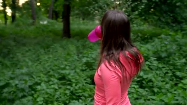 Mujer bebiendo agua y descansando mientras trota en el bosque — Vídeo de stock