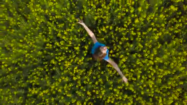 Jeune femme avec les bras tendus dans un champ de canola jaune 