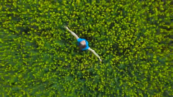 Jeune femme avec les bras tendus dans un champ de canola jaune 