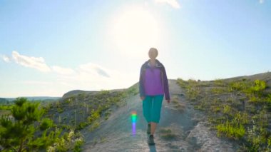 Kadın bir sırt çantası ile engebeli arazi üzerinde dolaşıyor. Hiking