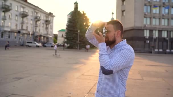 Mann läuft durch die Stadt und fotografiert Sehenswürdigkeiten mit Filmkamera — Stockvideo