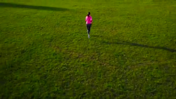 Женщина бежит по стадиону на закате, вид сверху — стоковое видео