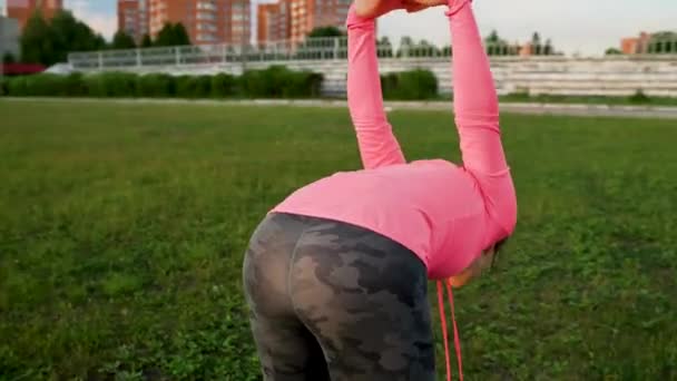Фитнес-женщина согревается и растягивается на стадионе перед бегом — стоковое видео