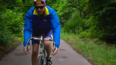 Orta yaşlı adam bir orman yolu boyunca bir yol bisikleti biniyor