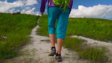 Kadın hiking bir sırt çantası ile engebeli arazi üzerinden sahiptir. Hiking