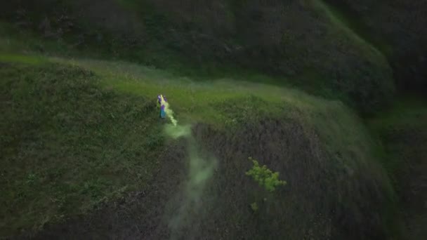 Turista mujer se para en la cima de una colina y agitando con una bomba de humo — Vídeos de Stock