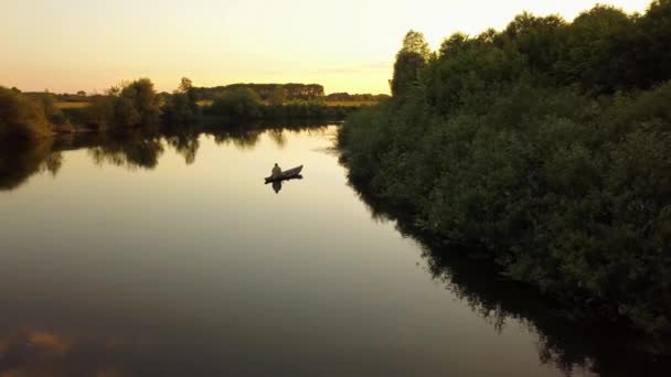 Silhuetten av en fiskare i en båt på en flod i solnedgången — Stockvideo