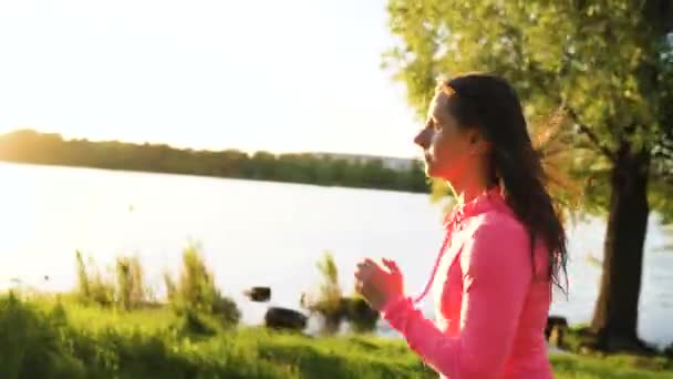 Woman runs through the park on the lake shore at sunset — Stock Video