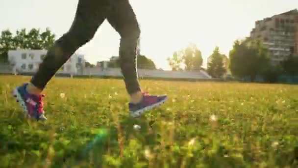 La mujer corre por el estadio al atardecer — Vídeos de Stock