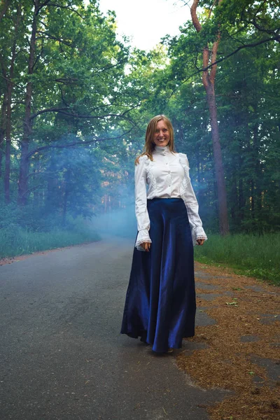 Woman in a beautiful outfit walks through the forest, enveloped — Stock Photo, Image