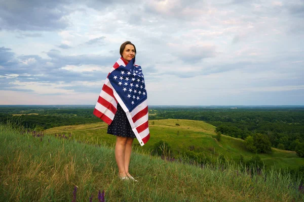 Trotse vrouw met een Amerikaanse vlag op de top van een heuvel is permanent — Stockfoto