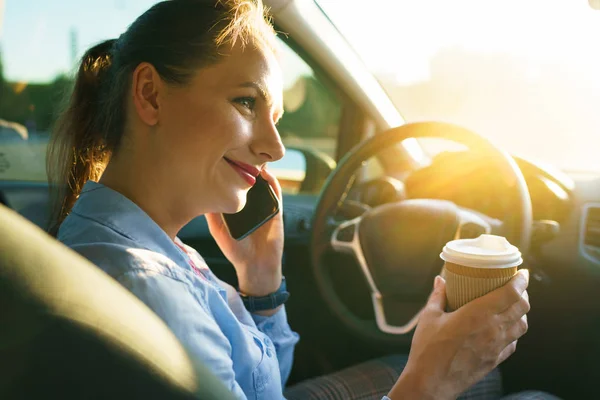 Mujer joven hablando en un teléfono inteligente y beber café mientras dr — Foto de Stock