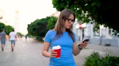 Kadın smartphone ve içme kahve sokakta yürürken kullanır