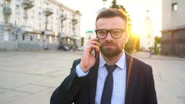 Dostum smartphone üzerinde konuşmak ve içme kahve yürüyüş sokak aşağı