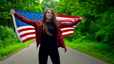 Bize bayrağı olan genç kadın ormanda paten ve başka bir kişinin elini tutar