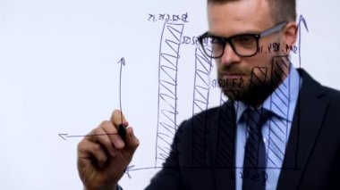 Adam bir modern cam ofis başarı için umutları hesaplama çeşitli büyüme çizelgeleri, çizer