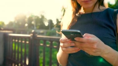 Gün batımında - arkadan görünüm sokakta yürürken bir smartphone kadın kullanır