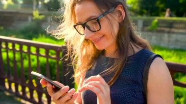 Gün batımında sokakta yürürken bir smartphone kadın kullanır