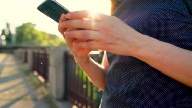 Bir akıllı telefon, açık havada gün batımı yakın çekim kullanan kadın