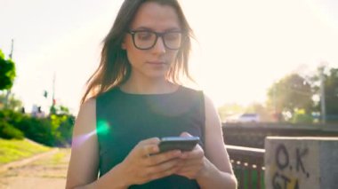Gün batımında sokakta yürürken bir smartphone kadın gözlük kullanır