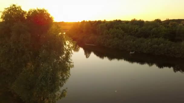 Silhouette d'un pêcheur dans un bateau sur une rivière au coucher du soleil 