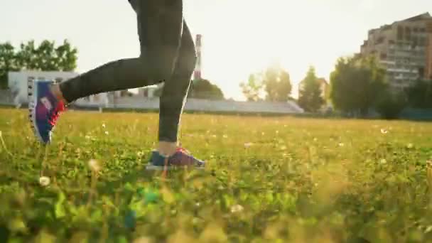 La mujer corre por el estadio al atardecer. Movimiento lento — Vídeos de Stock