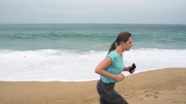 Mulher atlética correndo pela praia. Movimento lento — Vídeo de Stock