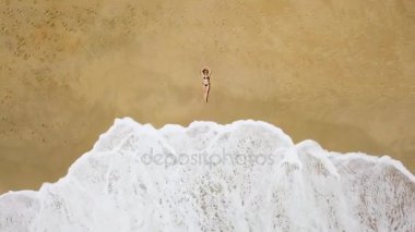 bir kadının yalan bir Kumsalı ve dalgalar üzerinde bir bikini hava atış onun ayakları yıkamak