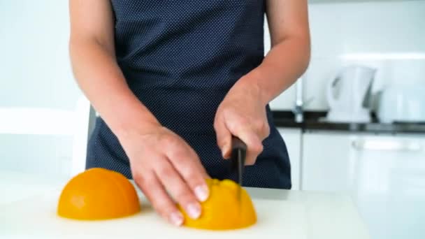 Жінка ріже апельсин на сучасній кухні — стокове відео