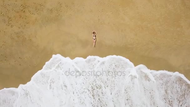 Bir kadının yalan bir Kumsalı ve dalgalar üzerinde bir bikini hava atış onun ayakları yıkamak — Stok video