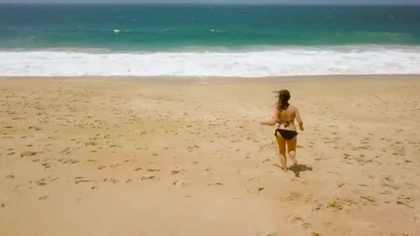 Bikini da spiaggia donna spensierata correre verso l'acqua sulla spiaggia. Pittoresca costa oceanica del Portogallo — Video Stock