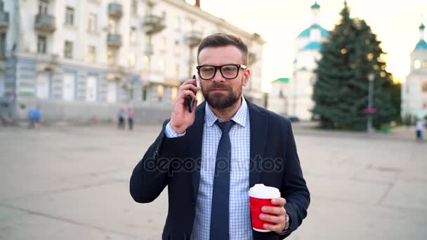 Mann spricht mit Smartphone und trinkt Kaffee auf der Straße. Zeitlupe — Stockvideo