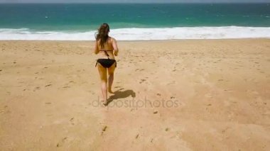 Plaj bikini kadın akan suyun için sahilde kaygısız. Portekiz kıyısında pitoresk okyanus