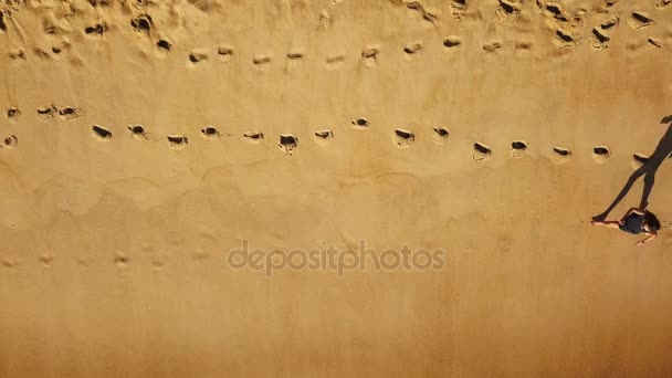Vista superior de una mujer corriendo descalza a lo largo de la playa de arena húmeda océano — Vídeo de stock