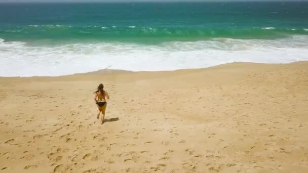 海滩比基尼女人无忧无虑在沙滩上跑到水。如诗如画的海洋葡萄牙海岸 — 图库视频影像