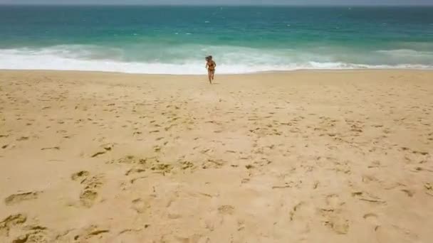 Bikini de playa mujer despreocupada corriendo del agua en la playa. Pintoresca costa oceánica de Portugal — Vídeo de stock