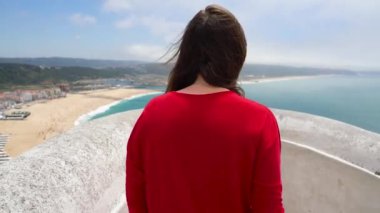 Kırmızı elbiseli kadına bir görünüm Nazare, Portekiz yakınındaki okyanus kıyılarının sahiptir