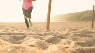 Koşu ayakkabıları - kadın ayakkabı bağcıklarımı kumsalda gün batımında bağlıyor.