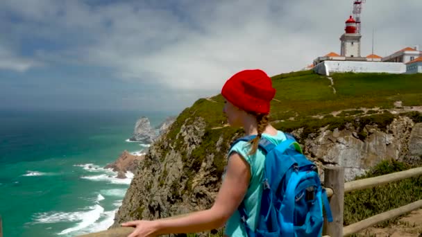 Kobieta z plecakiem oferuje widoki wybrzeża Oceanu w pobliżu latarni morskiej — Wideo stockowe