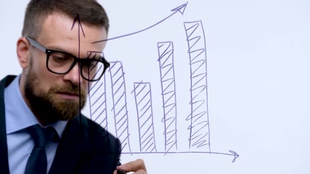 Homem desenha vários gráficos de crescimento, calculando perspectivas de sucesso em um escritório de vidro moderno — Vídeo de Stock