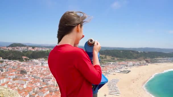 Turista femminile che usa un binocolo a gettoni in alta collina e guarda il paesaggio urbano di Nazareth, Portogallo — Video Stock