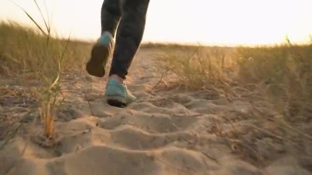 Pernas femininas correndo ao longo de uma praia de areia para o oceano. Movimento lento — Vídeo de Stock